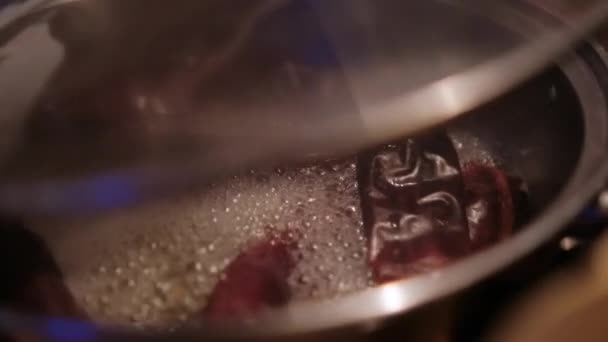 Kırmızı kuru biberler, cam kapaklı pişirme kabında kaynıyor. — Stok video