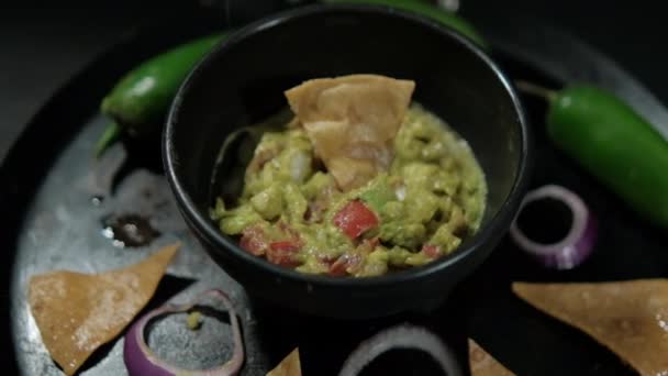 Чаша гуакамоле на мексиканском комале, украшенная чипсами и овощами — стоковое видео