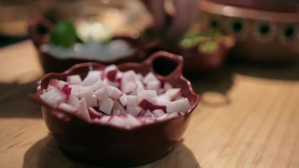 Глиняные горшки с рубленой редиской, луком, салатом и лаймами на деревянном столе — стоковое видео