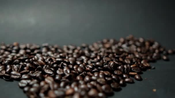 Haufen gerösteter Kaffeebohnen auf schwarzer Oberfläche — Stockvideo
