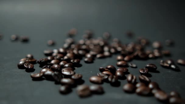 Куча жареных кофейных зерен выливается на черную поверхность — стоковое видео