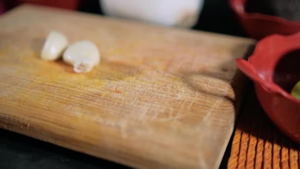 Dos dientes de ajo fresco en una tabla de cortar de madera — Vídeos de Stock