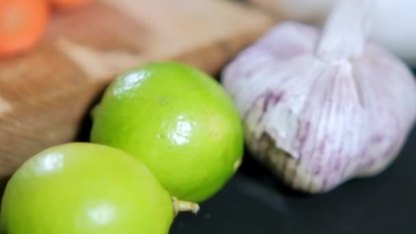 Dva limetky, česnek, cibule a více zeleniny nad černým povrchem — Stock video