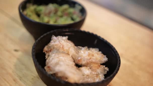 Bowls of pork rinds and guacamole on wooden surface — Stock Video