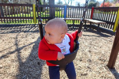 Arkaplanı ahşap çitlerle sallanan sevimli bebek.