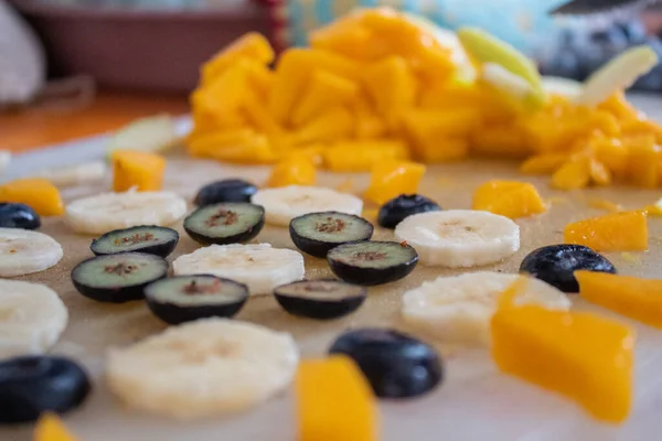 Banaan, mango en bosbessenschijfjes op snijplank — Stockfoto