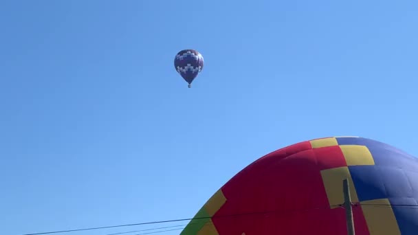 Mavi gökyüzünün altında renkli bir sıcak hava balonunu ısıtıp şişiriyor. — Stok video