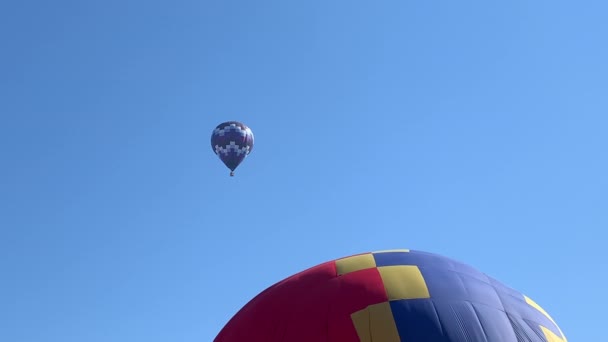 Нагрівання і надування барвистої повітряної кулі під блакитним небом — стокове відео