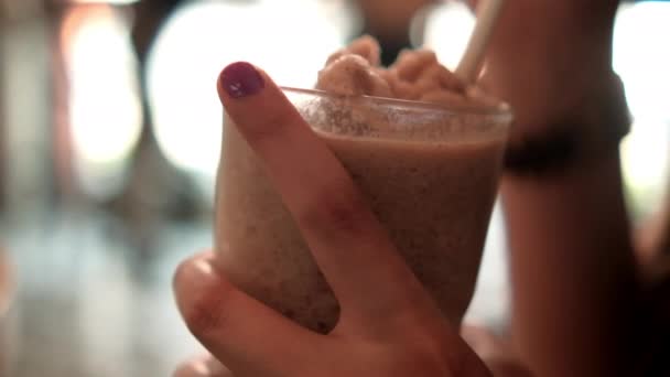 Kvinnliga händer som håller frappuccino i glas med suddig bakgrund — Stockvideo