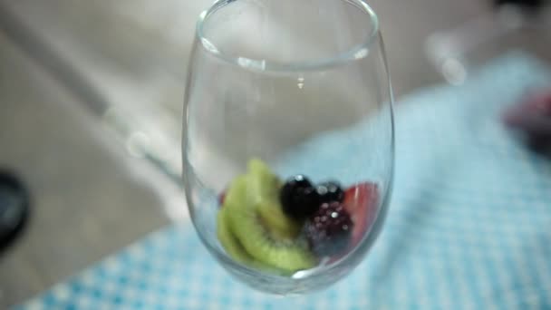 Strawberry dan kiwi iris dalam gelas anggur dengan latar belakang kabur — Stok Video