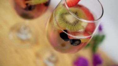 Çiçeklerle çevrili ahşap yüzeyde çilek ve kivi dilimli içecekler