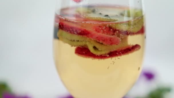 Пийте зі скибочками полуниці та ківі у винному келиху з білим тлом — стокове відео