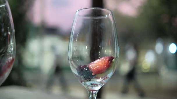 背景がぼやけているワイングラスの中のイチゴとキウイスライス — ストック動画