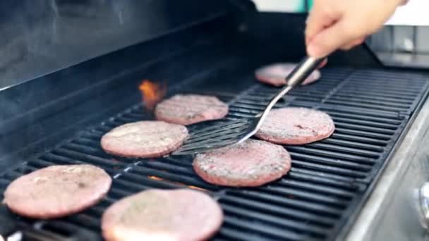Masculino mano volteo carne de hamburguesa cruda en parrilla barbacoa de hierro — Vídeo de stock