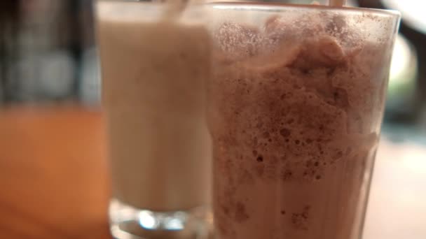 Smaklig utseende frappuccino och milkshake i glas med suddig bakgrund — Stockvideo