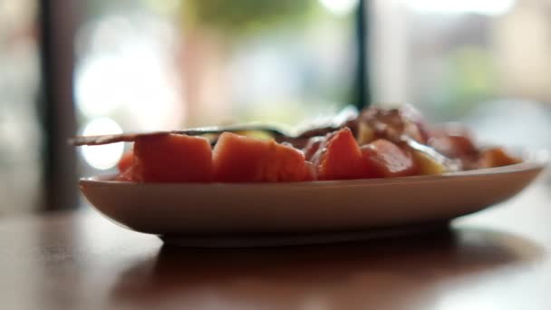 Тарелка нарезанных фруктов со сливками, овсянкой и вилкой сверху — стоковое видео
