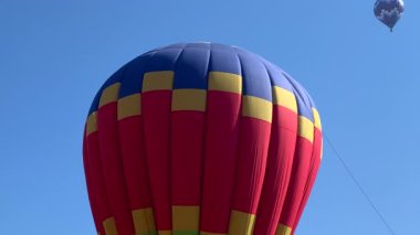 Mavi gökyüzünün altında renkli bir sıcak hava balonunu ısıtıp şişiriyor.