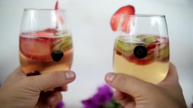 Meyve dilimleri ve beyaz arkaplanlı iki el şarap bardakları.