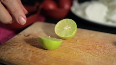 Tahta kesme tahtasına limon dilimleyen eller.