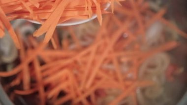 Soğan ve domates dilimleriyle tencereye rendelenmiş patates ve havuç ekliyorum.