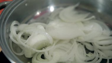 Ahşap kaşık karıştırıyor soğan dilimleri pişiriyor tencerede