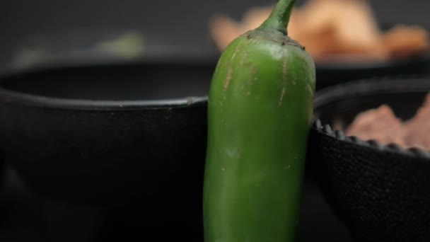 Перець чилі, що спирається на миски чіпсів тортильї та смажених бобів — стокове відео