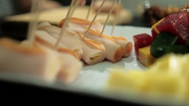 Rollos de jamón, pasta de frutas en cubitos y cubos de queso en un plato — Vídeos de Stock