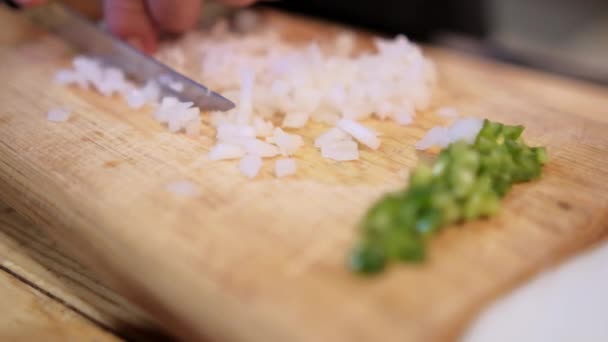 Mãos cortando cebola e pimentão verde em uma tábua de corte — Vídeo de Stock