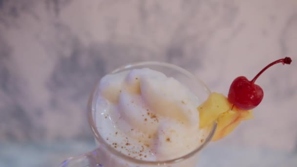 Vanilj milkshake med frukt på kanten och ovanför vit marmor bakgrund — Stockvideo