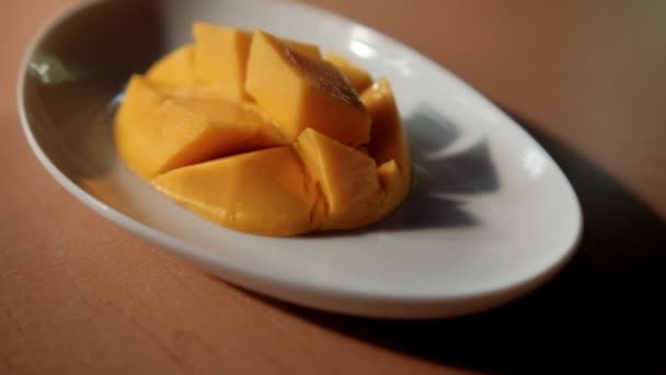 Ψιλοκομμένο μάνγκο σε λευκό πιάτο πάνω από το καφέ τραπέζι — Αρχείο Βίντεο