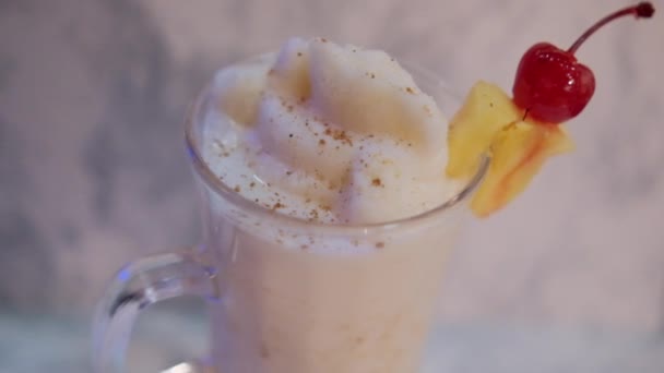 Vanille milkshake met fruit op de rand en boven witte marmeren ondergrond — Stockvideo