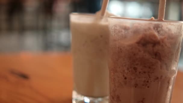 Frappuccino de aparência saborosa e milkshake em óculos com fundo embaçado — Vídeo de Stock