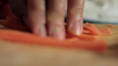 Eller kesme tahtasındaki tatlı patates dilimlerini kesiyor.