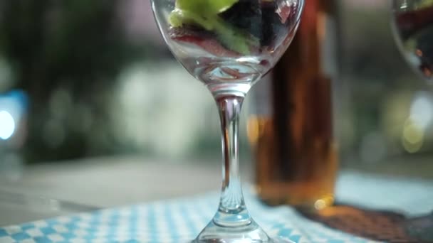 Fatias de morango e kiwi em copo de vinho com fundo embaçado — Vídeo de Stock