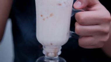 Adam elinde tutuyor ve samanla lezzetli vanilyalı milkshake içiyor.