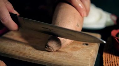 Tahta kesme tahtasının üzerinde büyük yer elması dilimleyen eller.