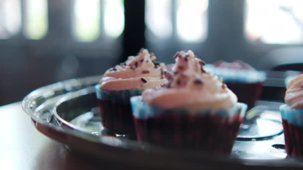 Три смачні кекси на круглому чорному підносі з вікном як фон — стокове відео