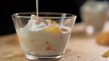 Şeftali kabına yoğurt dök ve ahşap yüzeyin üzerine krema dök.