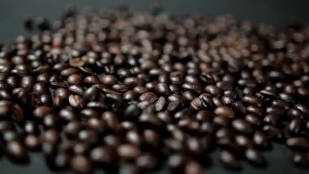 Куча жареных кофейных зерен движется по черной поверхности — стоковое видео