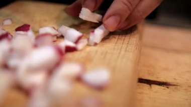 Kesme tahtasında taze turp doğrayan eller.