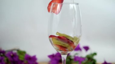 Beyaz arkaplanlı şarap kadehinde çilek ve kivi dilimleri.