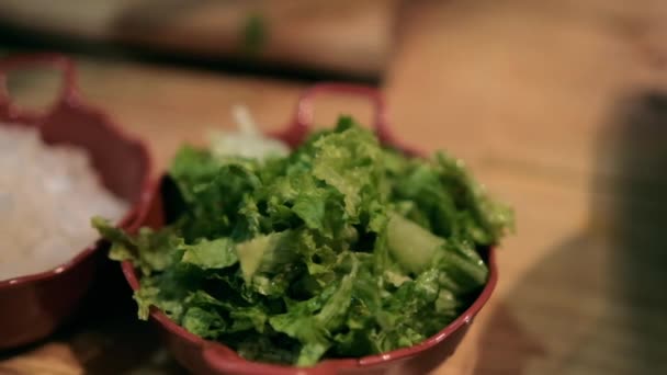 Vase de lut de salată verde, ridichi tocate, ceapă și lime pe masa de lemn — Videoclip de stoc