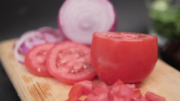 Gesneden tomaat en ui op snijplank boven zwart oppervlak — Stockvideo