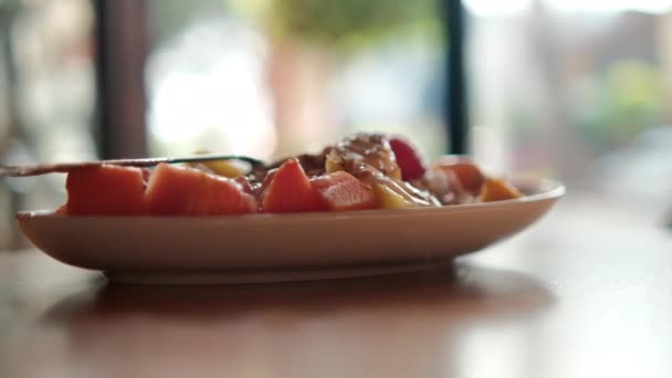 Plate of sliced fruit with cream, oatmeal, and fork on top — Stock Video