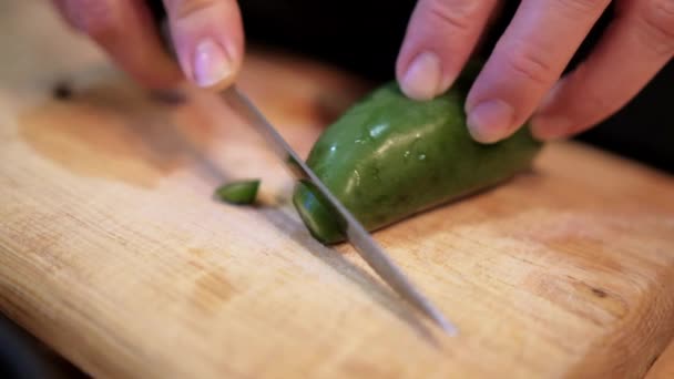 Handen langzaam snijden chili peper op snijplank — Stockvideo