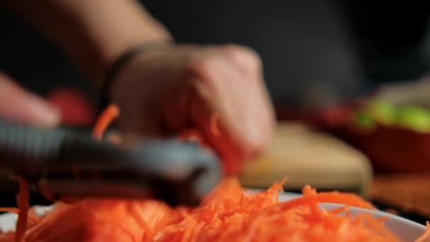 Mains pelant la carotte mince avec éplucheur de julienne au-dessus de la plaque blanche — Video