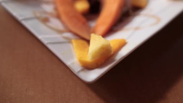 Свежие фруктовые ломтики и мед на квадратной фарфоровой тарелке — стоковое видео