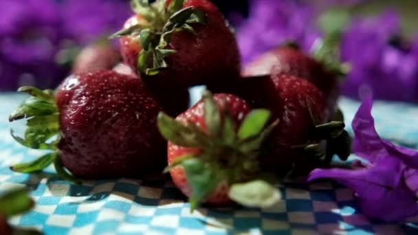 Tumpukan kecil stroberi dan bunga ungu pada taplak meja — Stok Video