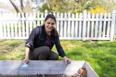 Güzel esmer kadın boş bir saksı kutusunda paskalya yumurtası saklıyor.