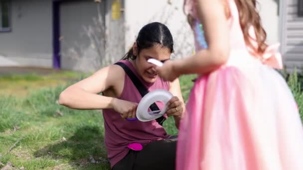 Чарівна маленька дівчинка і її мати вирізають барвисті паперові тарілки на передньому дворі — стокове відео